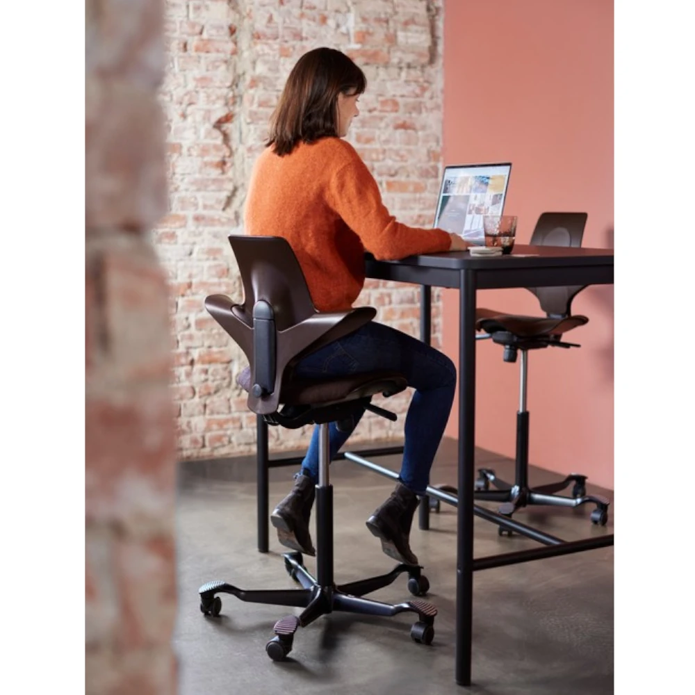 Frau sitzt auf HAG Capisco Puls 8020 Snow Plough Bürostuhl im Homeoffice